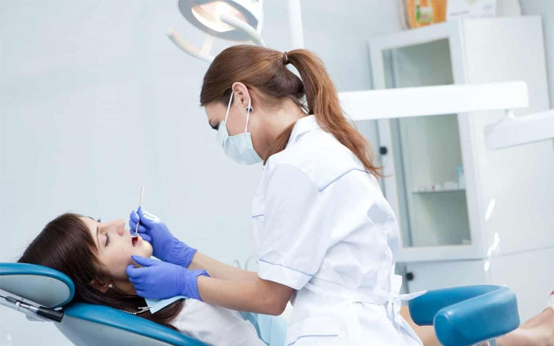 Hình ảnh bác sĩ đang tiến hành kiểm tra răng miệng tổng quát